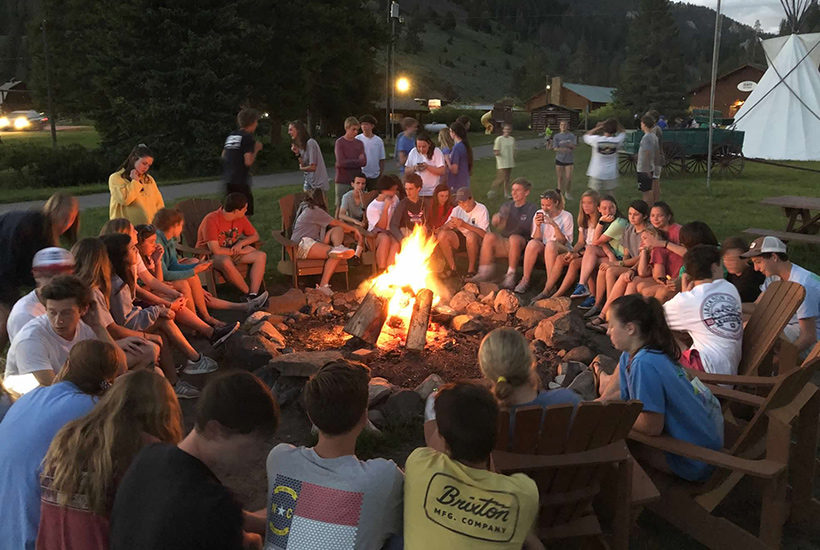 teen tour student group around campfire