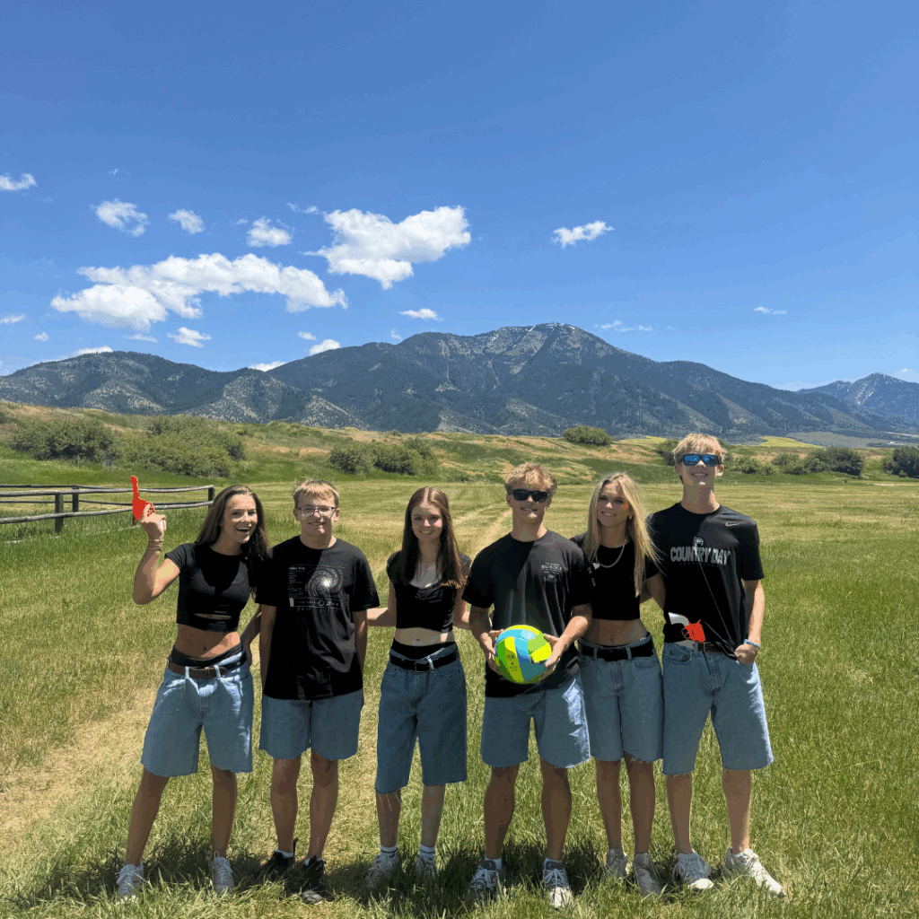 students in black t shirts and shorts playing volleyball at the ranch 