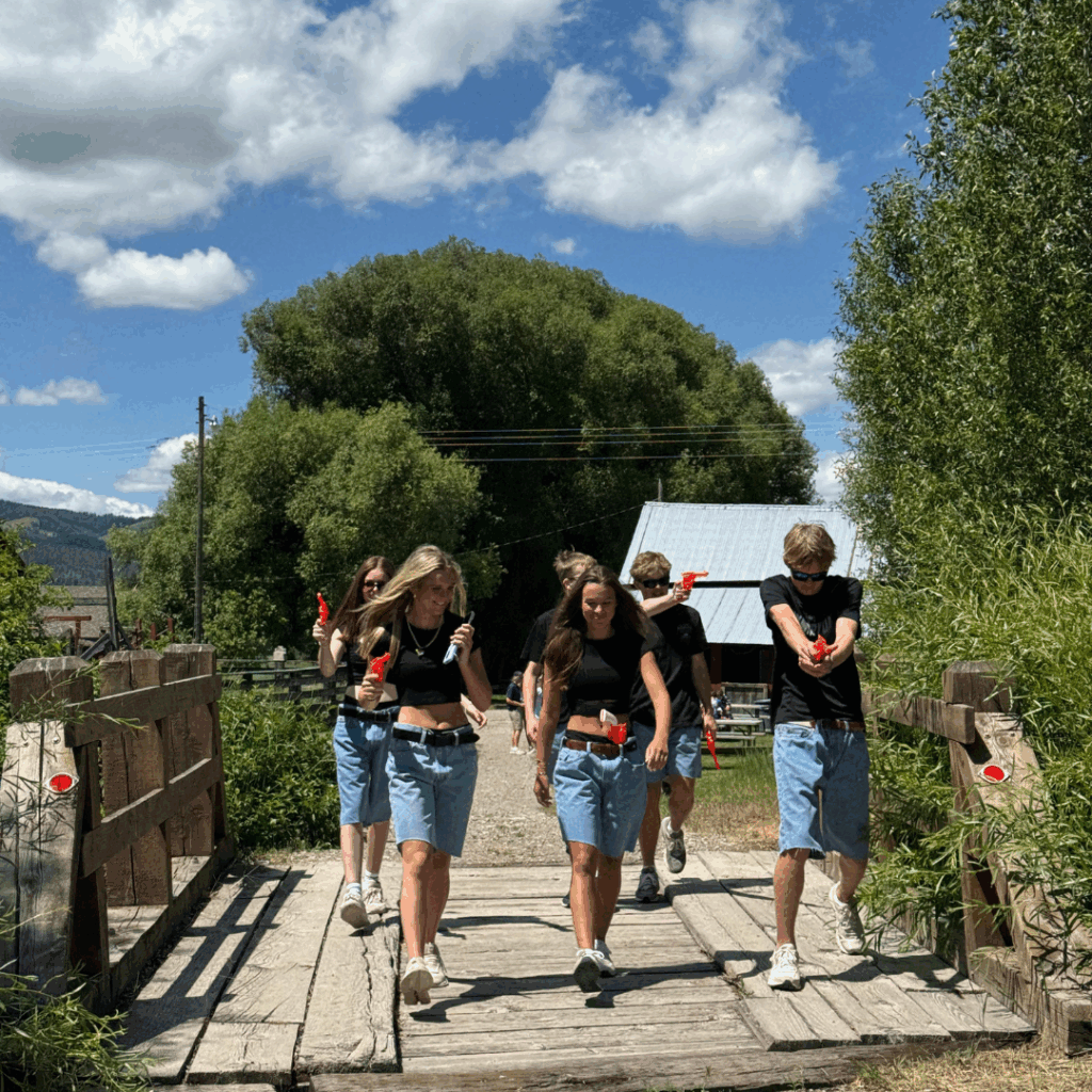 students in black t shirts walking toward camera with squirt guns 