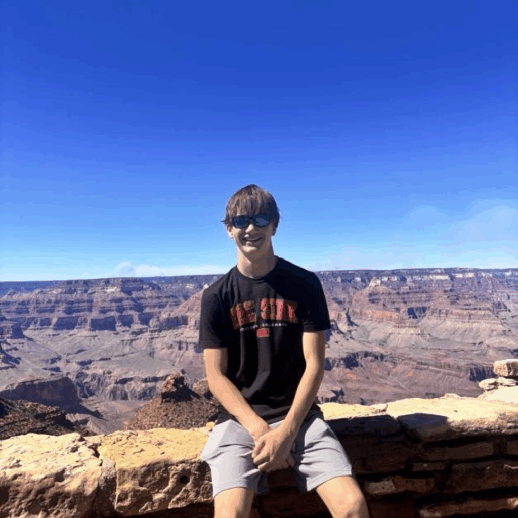 one student sitting on the ledge at the grand canyon