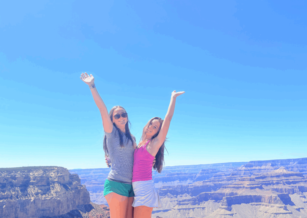 two students with raised arms at the grand canyon 