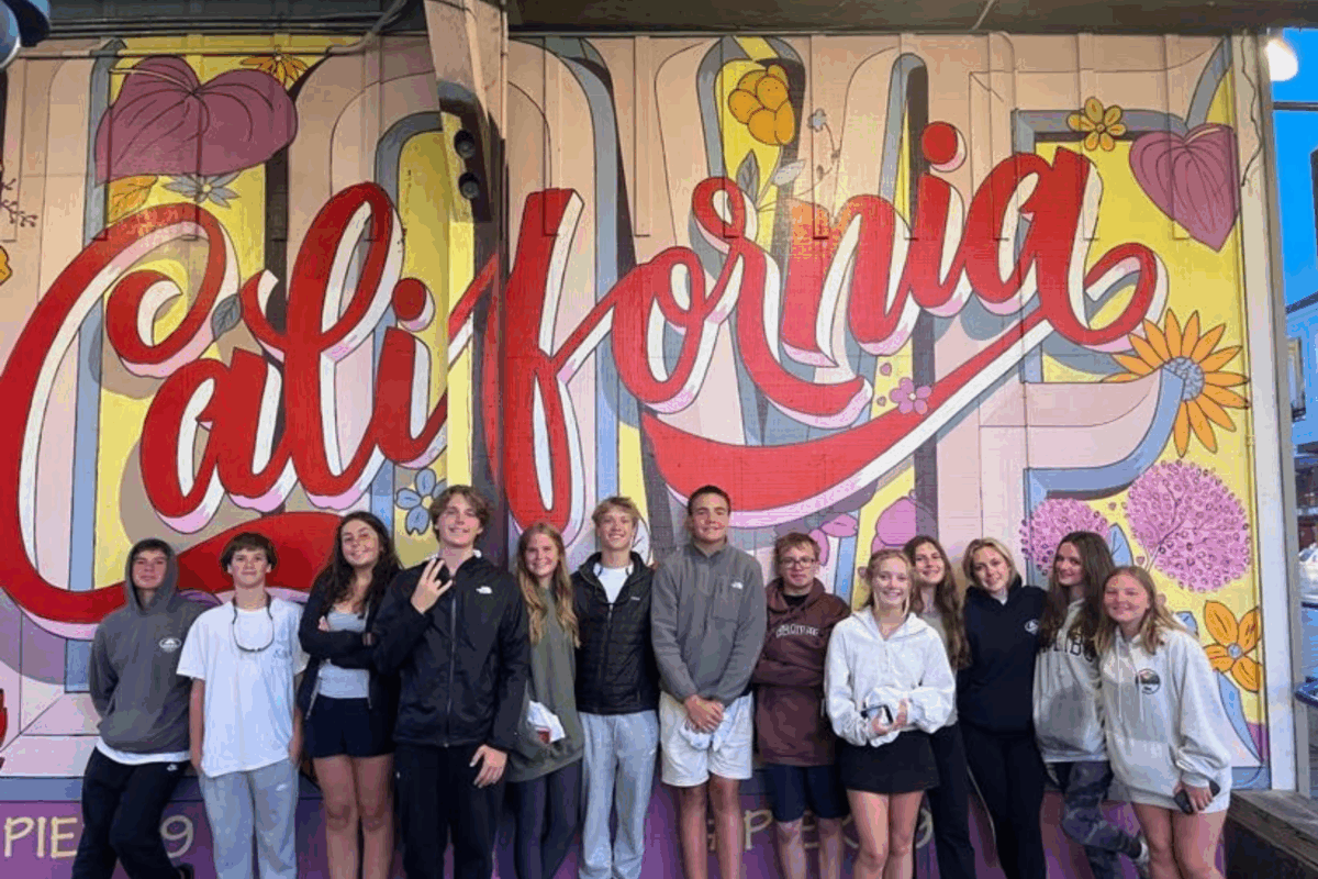 students standing in front of the california mural