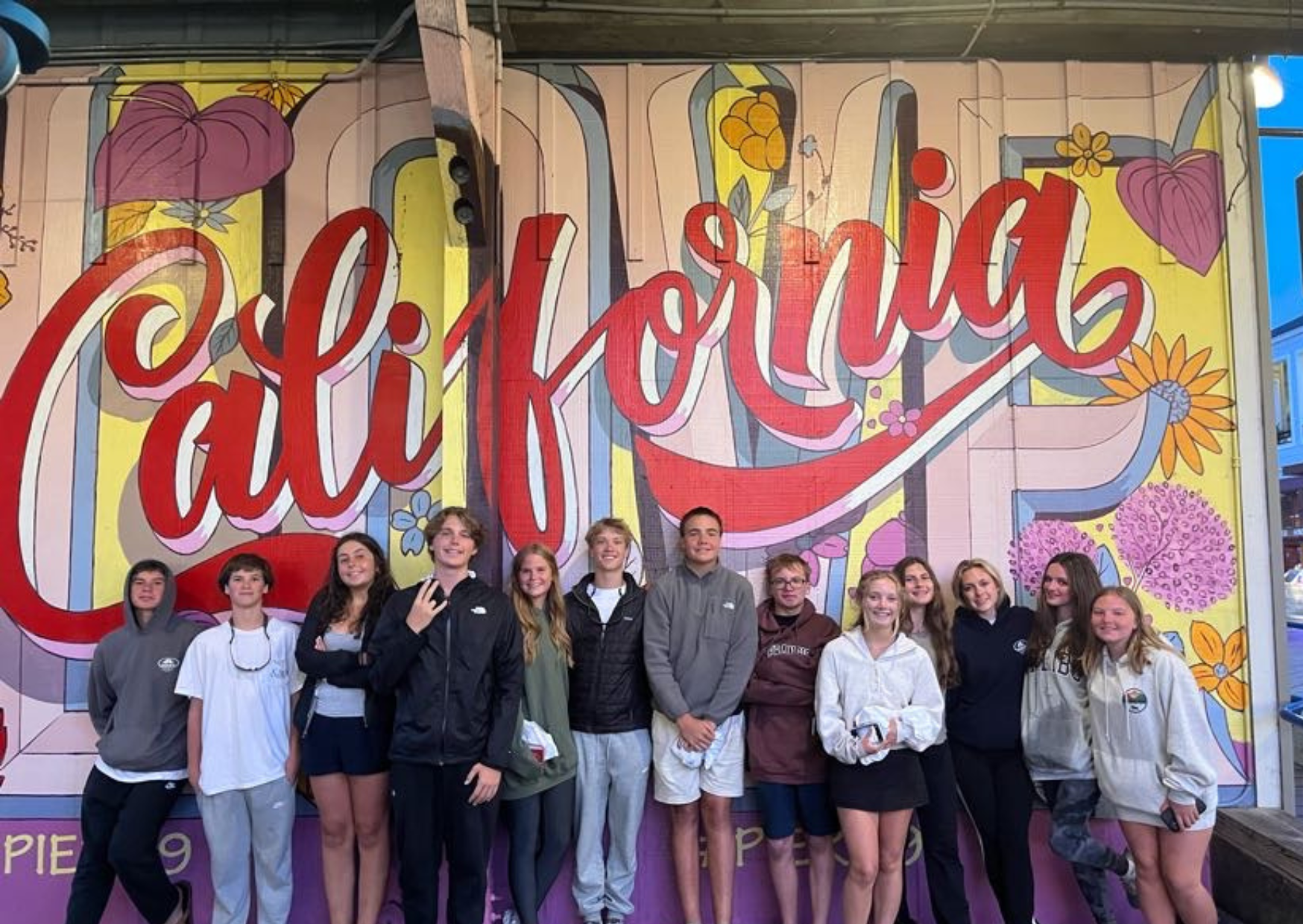 students standing in front of the california mural
