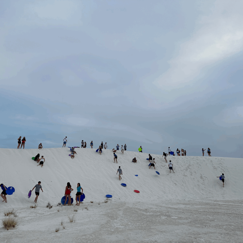 sand dunes and students climbing and sledding 