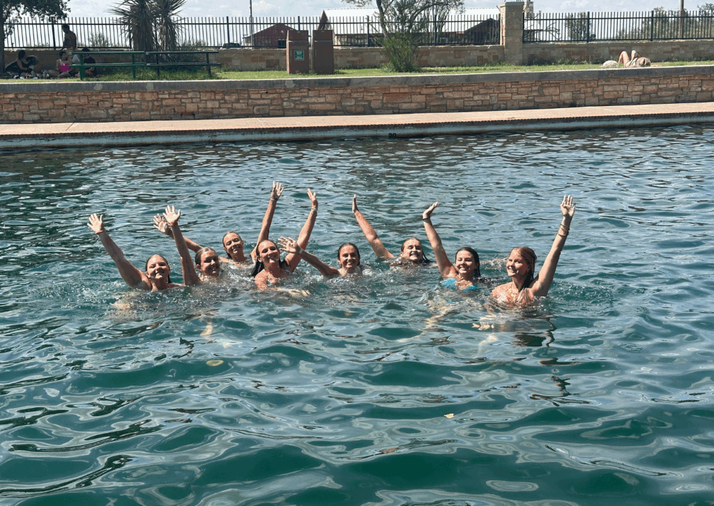 students swimming in the texas watering hole cooling off