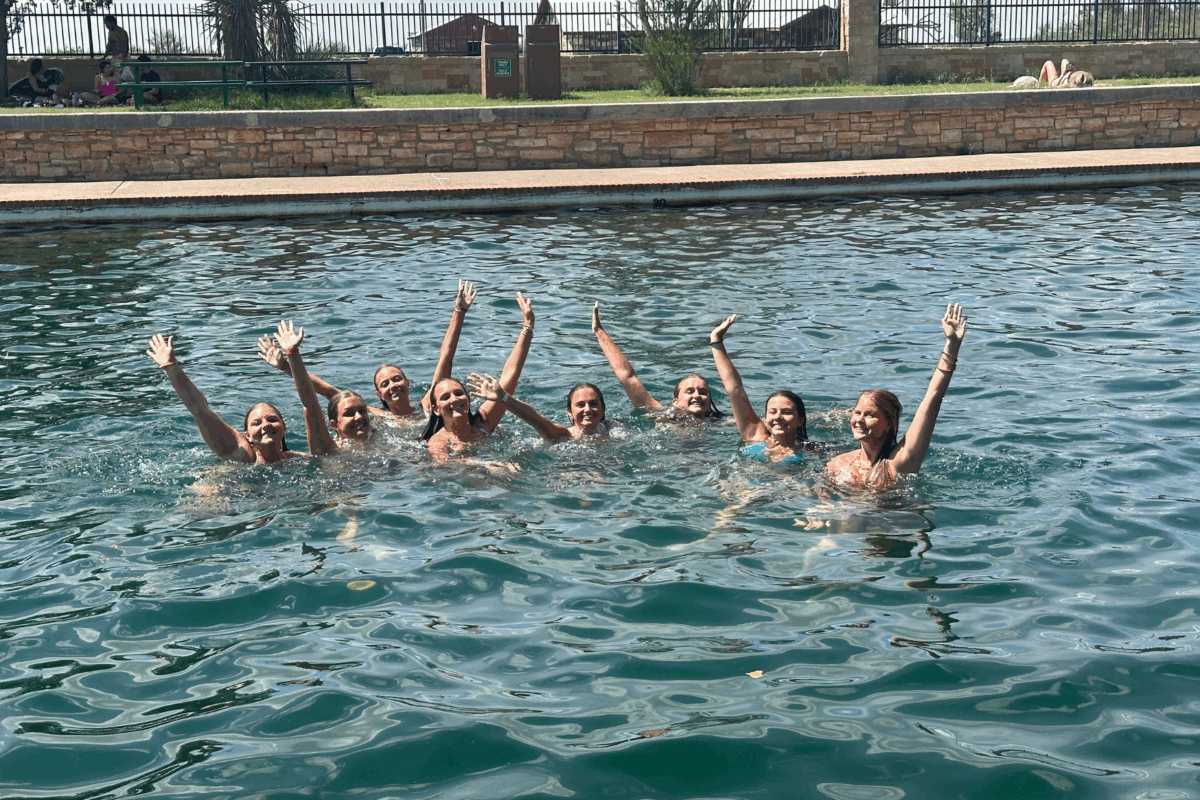 students swimming in the texas watering hole cooling off