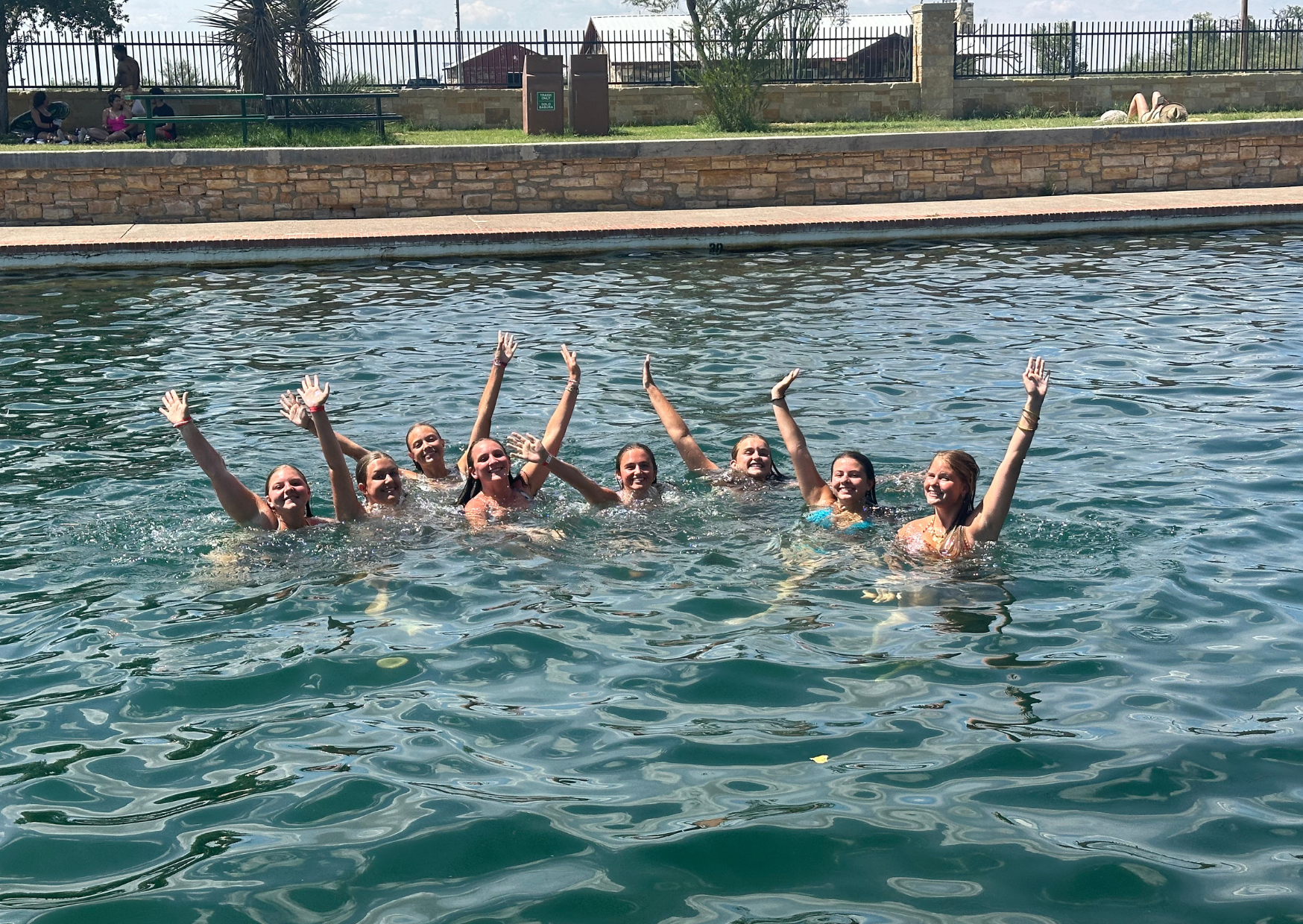students swimming in the texas watering hole cooling off