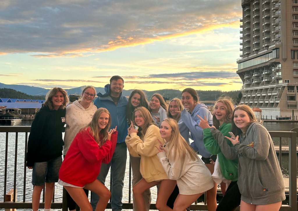 girls and one man in the group pointing toward the center while on their way to Seattle and watching sunset fro the waterfront