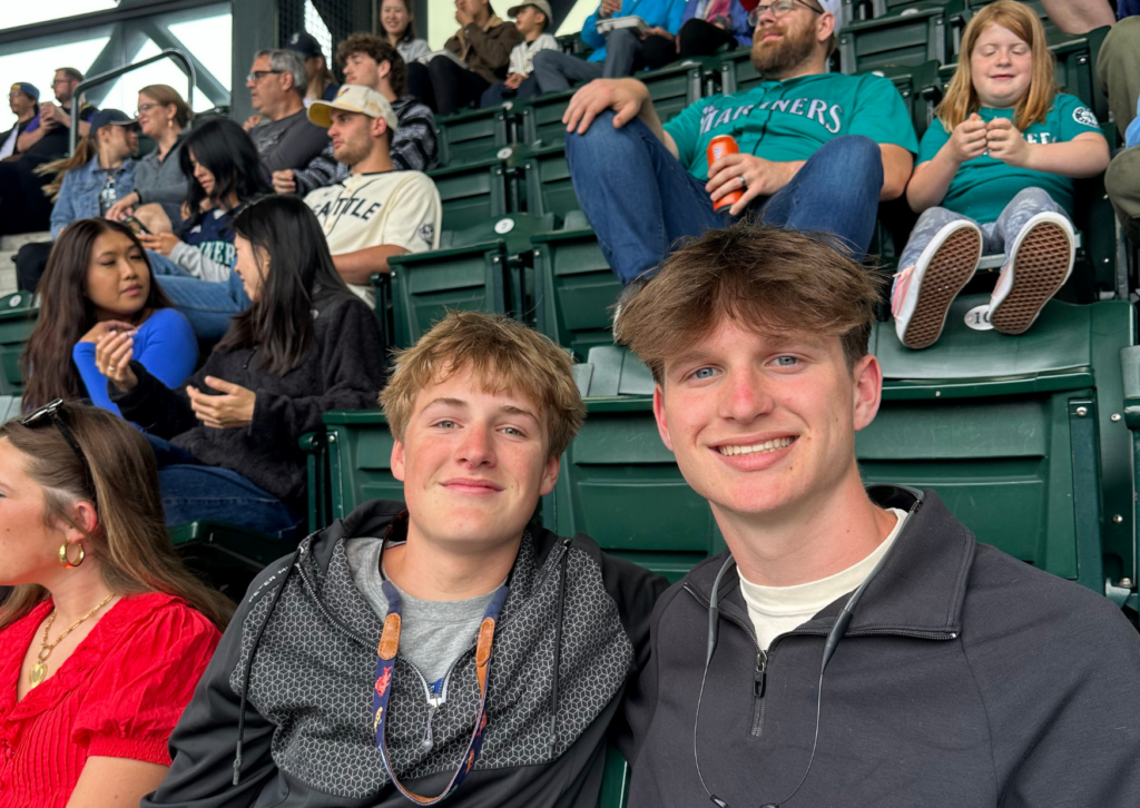 Two students smiling in the stands at a Seattle Mariners baseball game