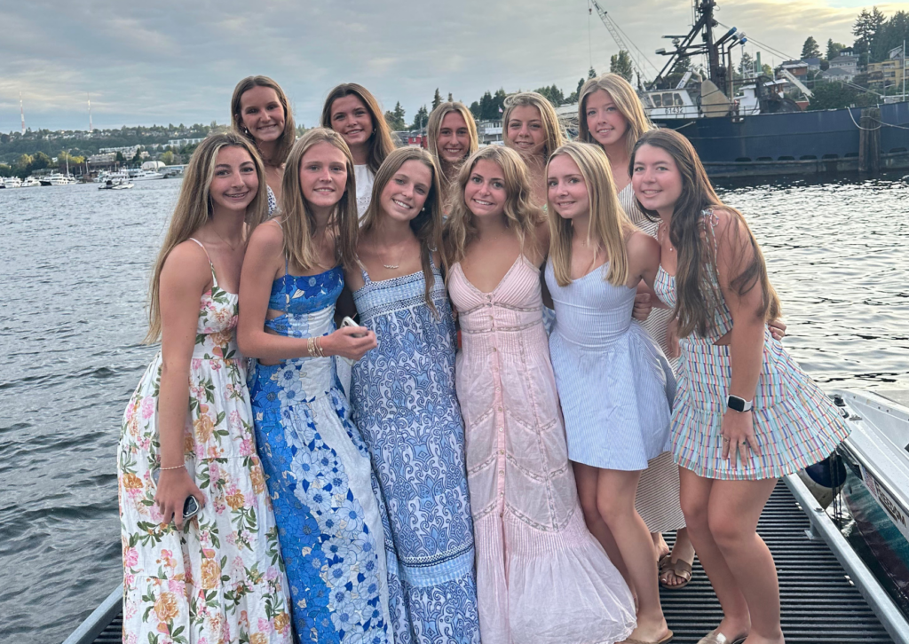Group of students dressed up in summer dresses posing on a dock by the Seattle waterfront at dusk