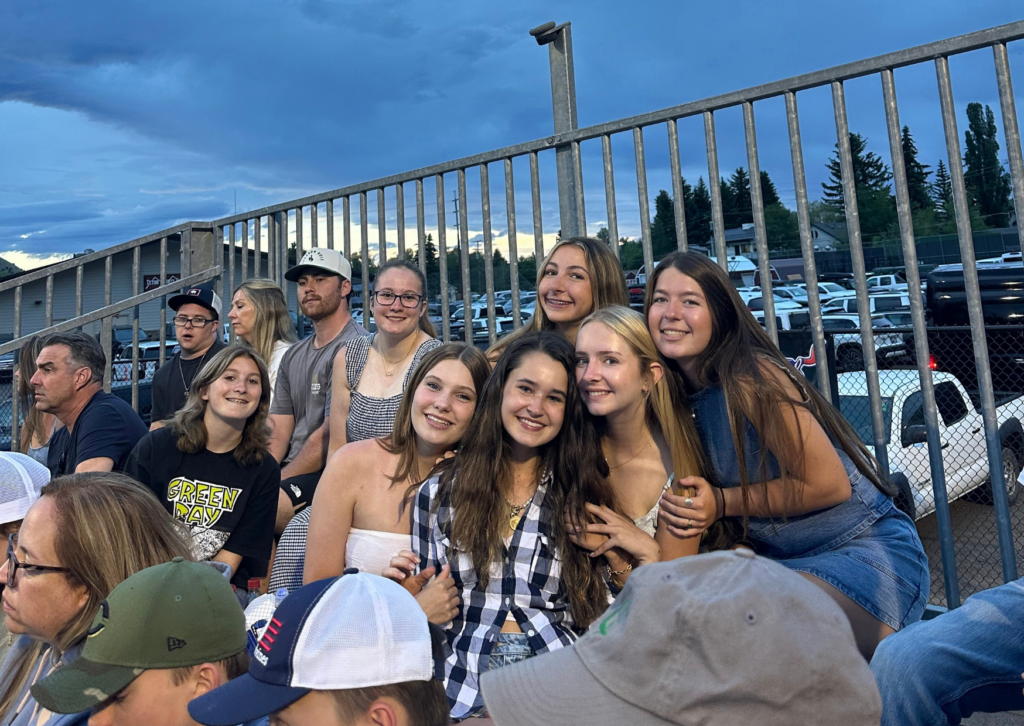 A group of teen girls smiling together in the grandstands at the Jackson Hole rodeo