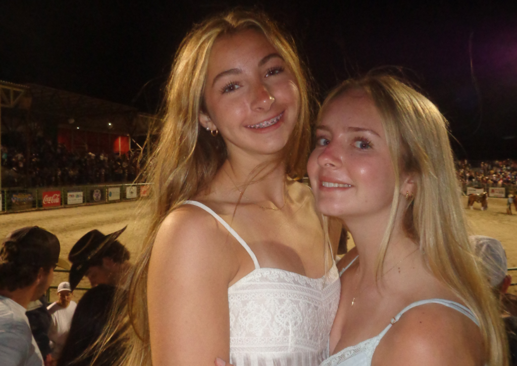 Two teen girls smiling together at the Jackson Hole rodeo arena at night