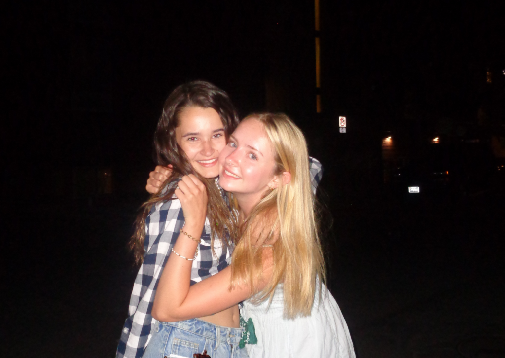 Two teen girls hugging and smiling together outside at night after the rodeo in Jackson
