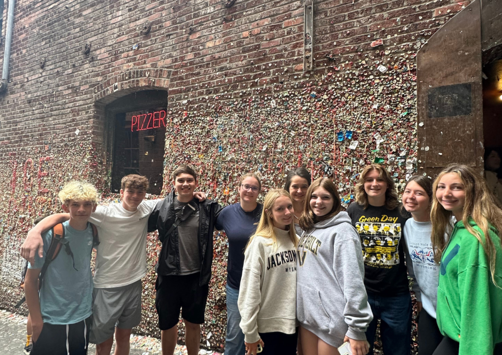 Students posing in front of the Seattle Gum Wall near Pike Place Market, with the colorful gum-covered brick walls behind them