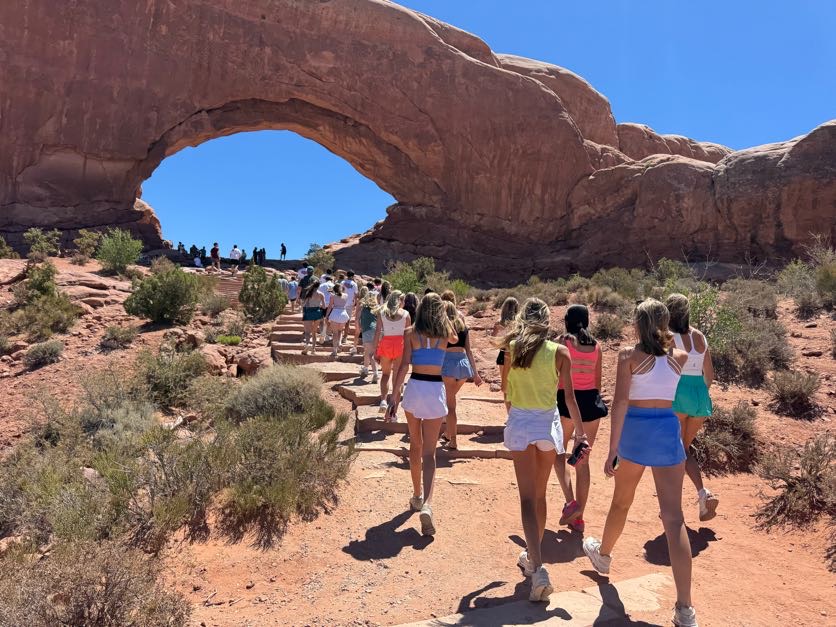 students walking away from camera toward hole in the rock