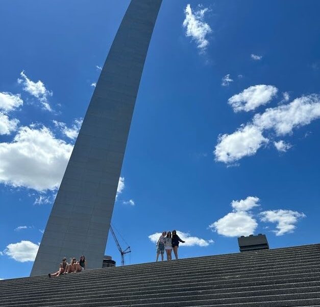 three friends on the stairs in front of the st. louis arch