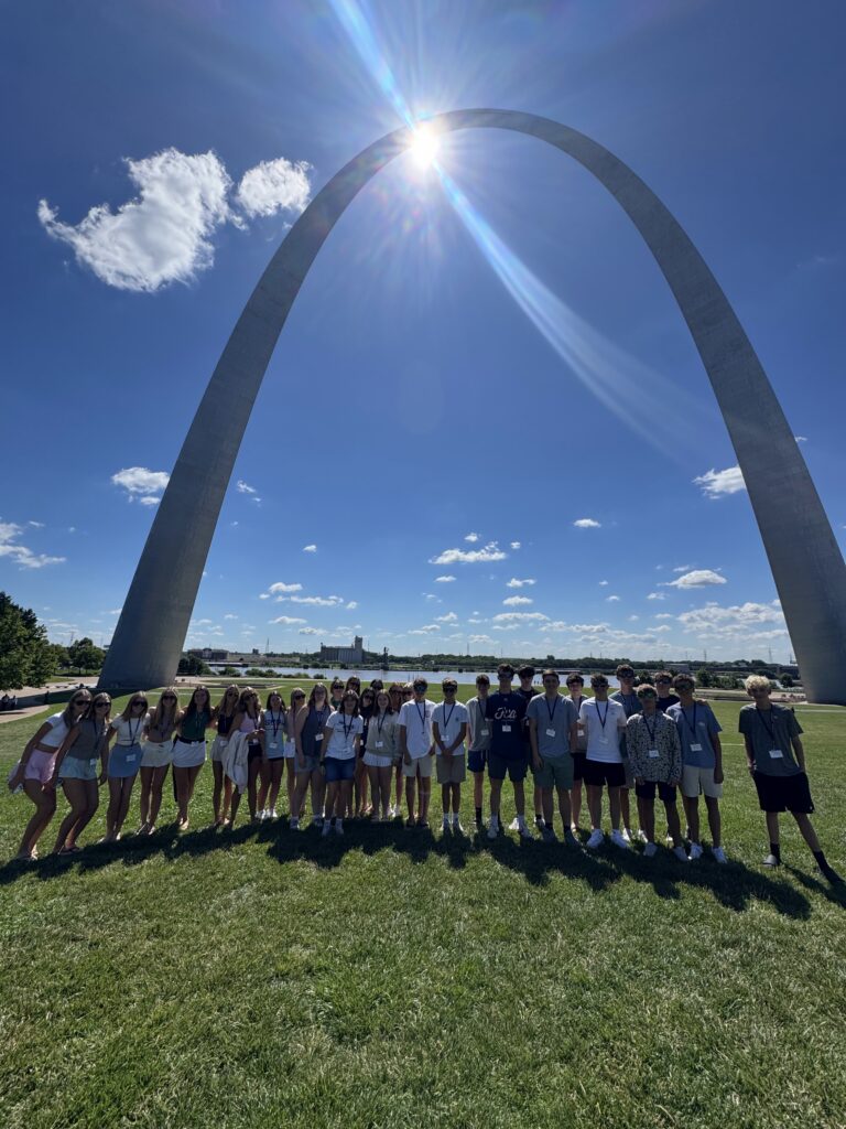 full group vertical standing in front of the st louis arch 