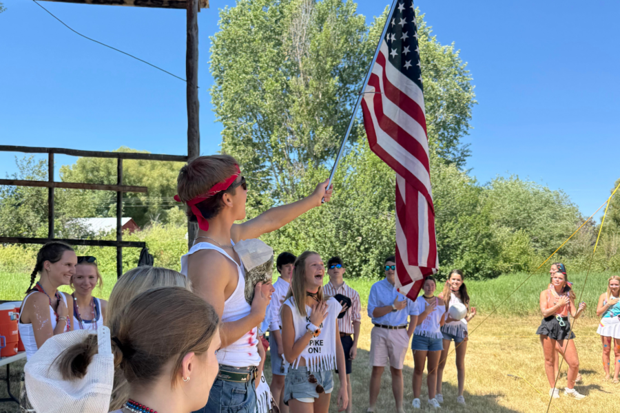 students raising american flag in costumers outside