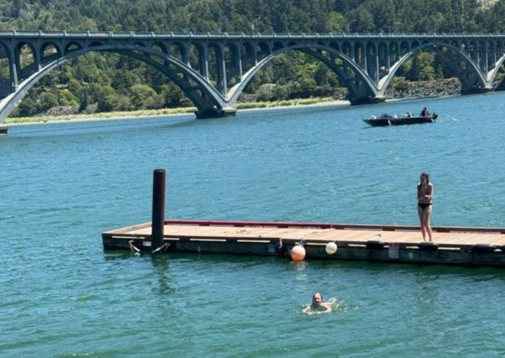students jumping into the river with bridge in the background