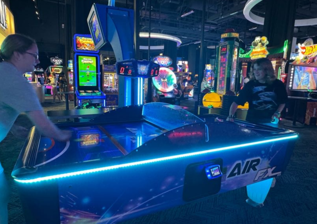 students playing air hockey at the arcade