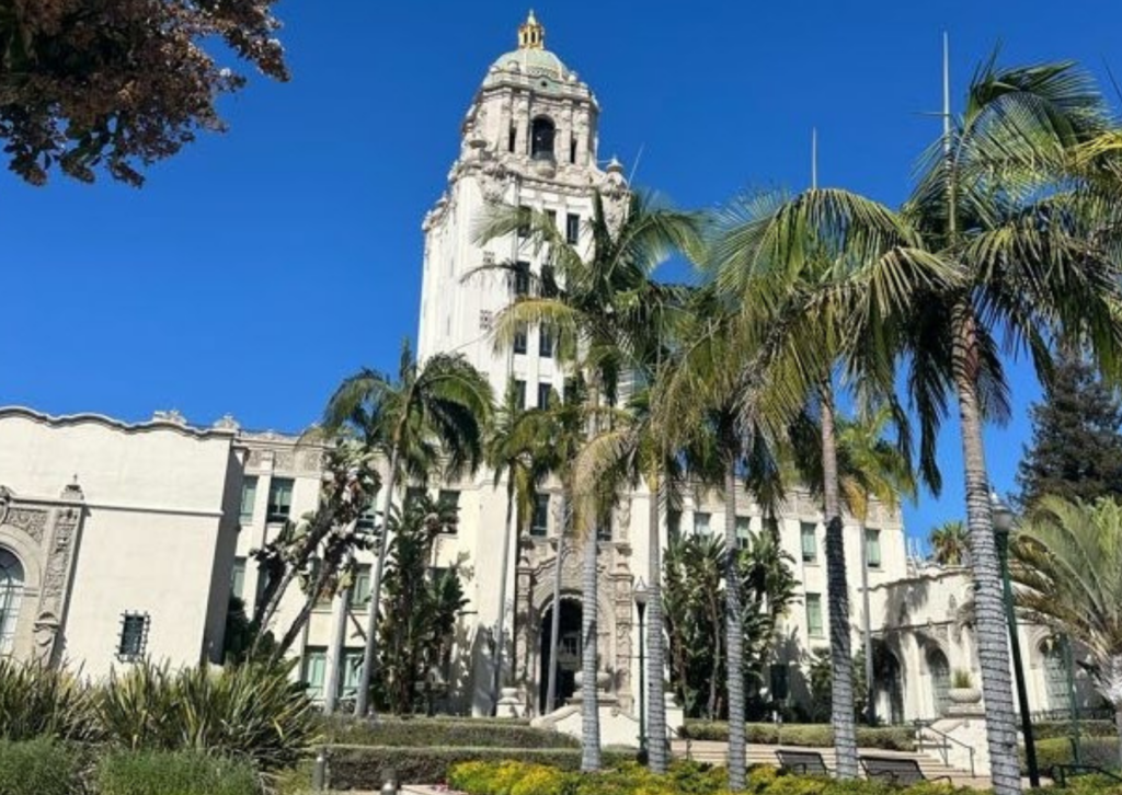 Beverly Hills City Hall's ornate tower surrounded by palm trees under a clear blue sky