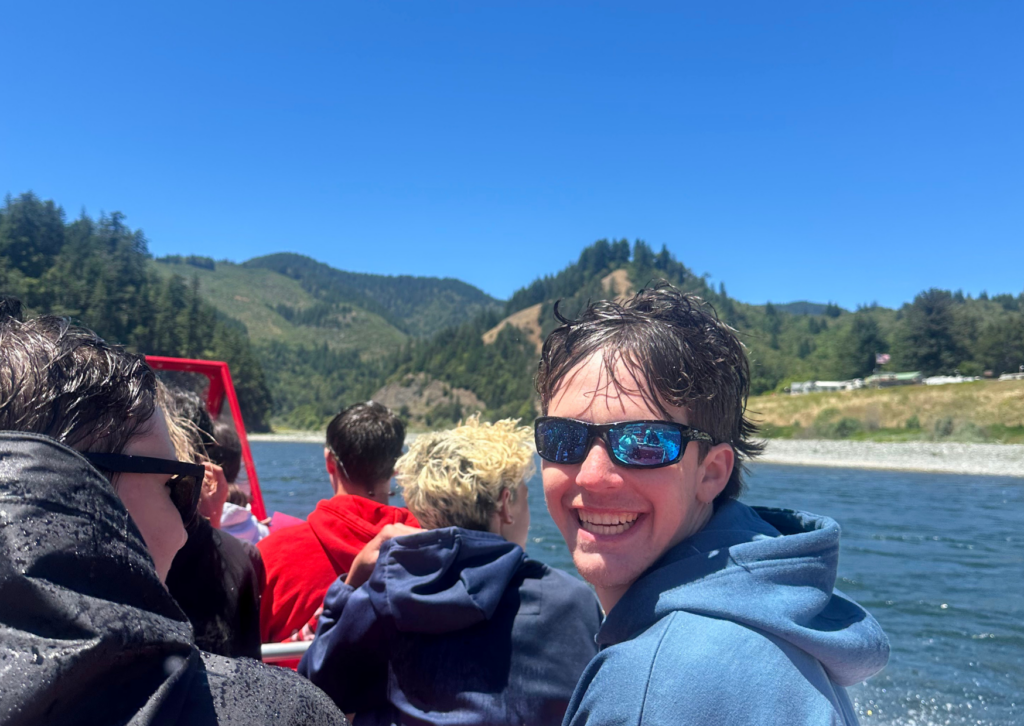 student in sunglasses looking directly at camera with wet hair from spray from jet boat
