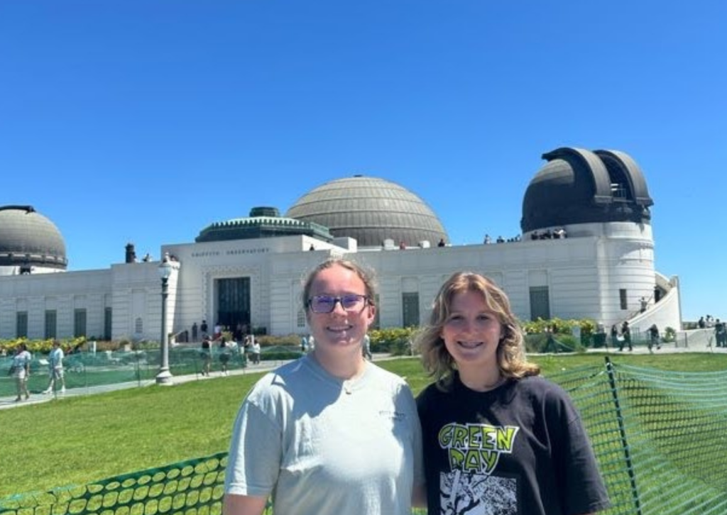 Two travelers posing in front of the Griffith Observatory's domes on a sunny day