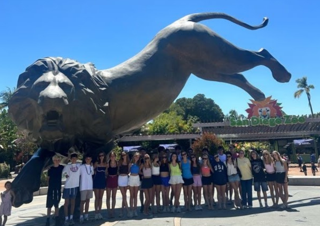 Group of travelers posing in front of the large lion statue at the San Diego Zoo entrance