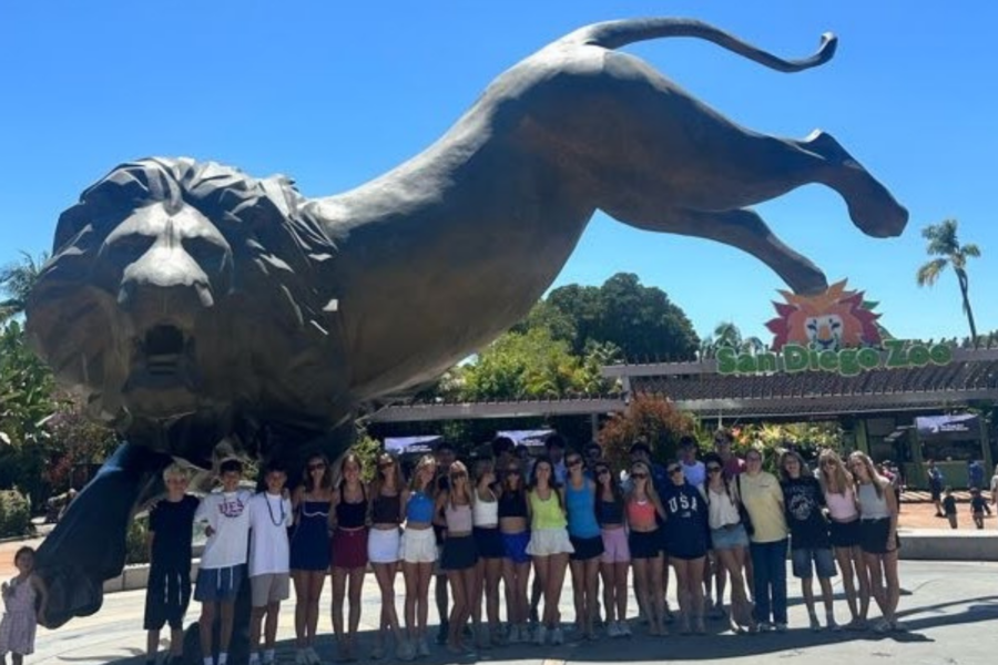Group of travelers posing in front of the large lion statue at the San Diego Zoo entrance