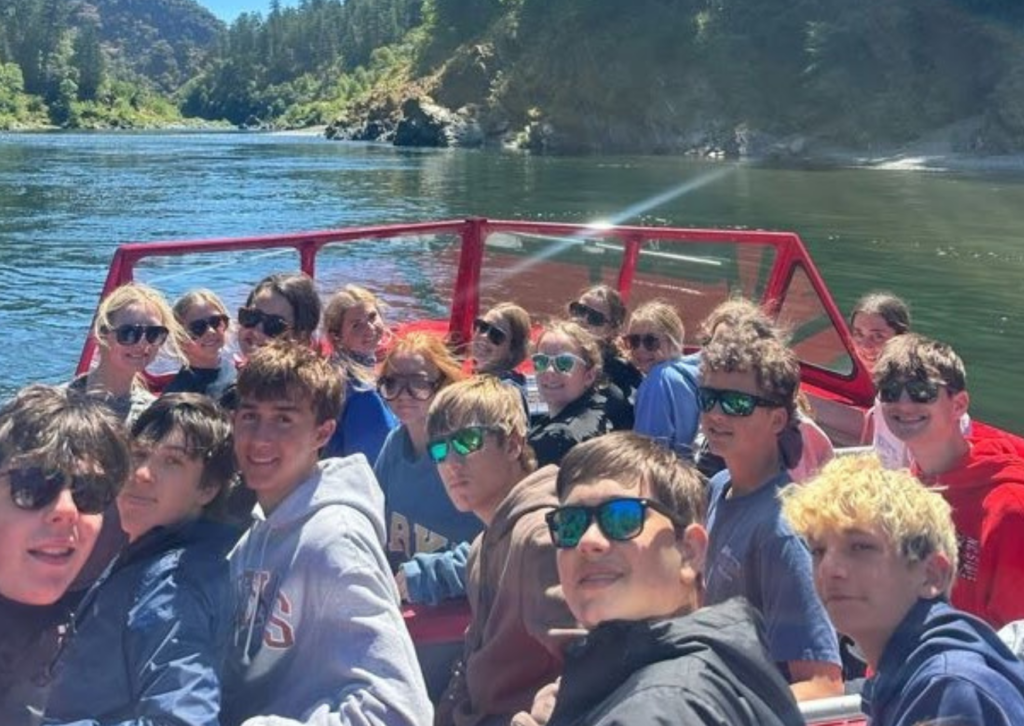 students looking back at camera from within the jet boat smiling