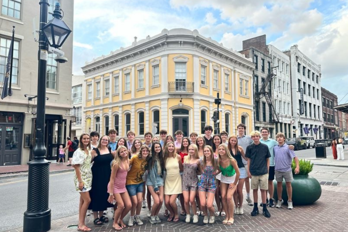 students standing in front of a yellow colonial building in new orleans