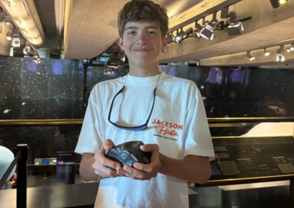 Teenage boy holding an ancient meteorite on display inside the Griffith Observatory